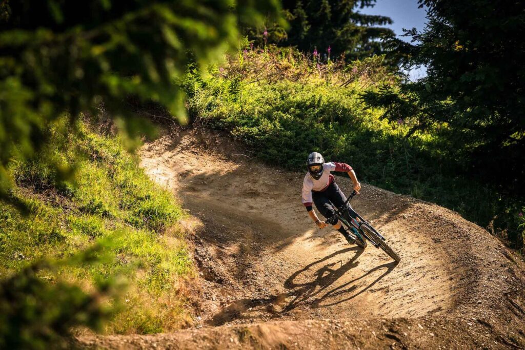 A man riding a mountain bike along a rugged dirt trail surrounded by trees and natural scenery.